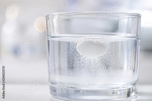 Bola efervescente disolviéndose en un vaso de agua clara en una mesa