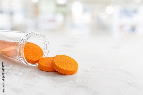 Pastillas de color naranja caídas de un frasco en una superficie