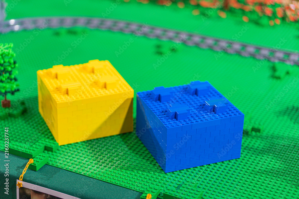 Naklejka premium Lego train set with two houses, one yellow and the other blue, on a green base - Kyiv, Ukraine - June 7, 2025