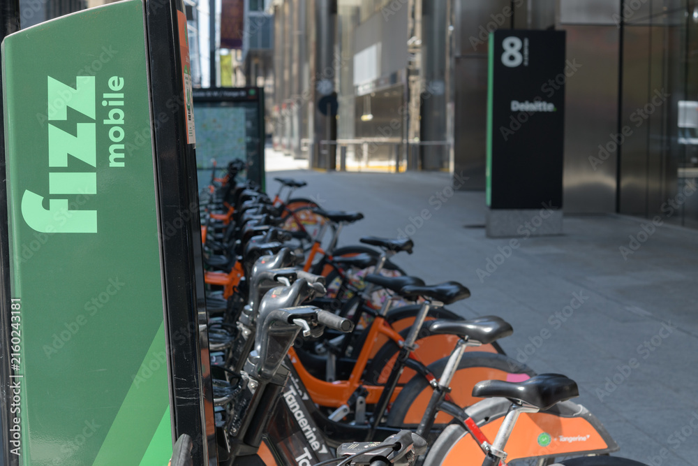 Fototapeta premium Bike Share Toronto rental vehicle docking station with Fizz Mobile and Tangerine Financial sponsor marketing on Adelaide St W
