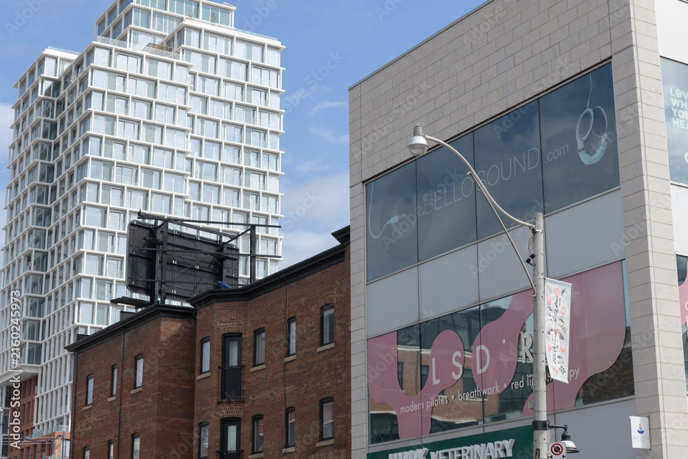 Naklejka premium (at right) 1073 Yonge St, location of Juno Veterinary, Blue Canoe Yoga, LSDR Studios, and BelloSound, a historic commercial block, and The James a recently built condo tower, Toronto