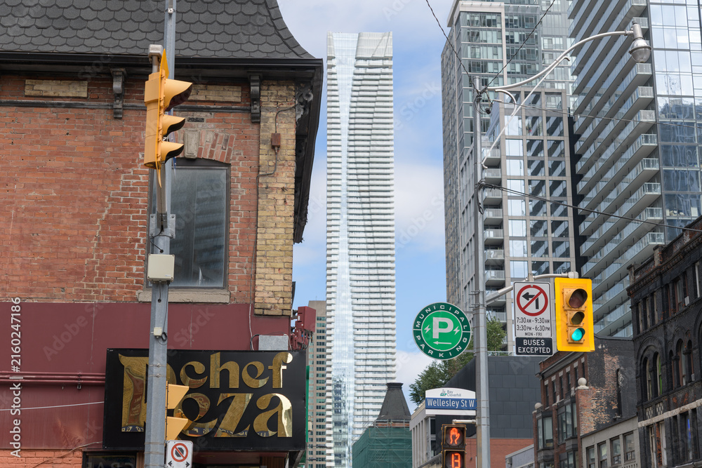 Fototapeta premium northwest corner of Wellesley St, looking north on Yonge St to Chef Reza (570 Yonge St) and a distant view of One Bloor East, Toronto