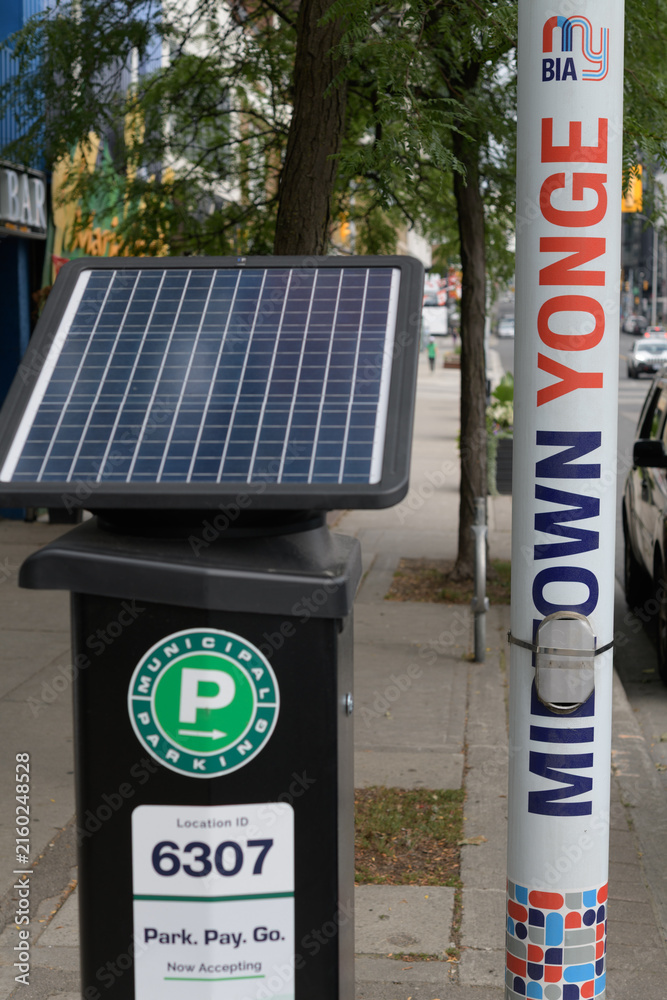 Fototapeta premium Municipal Parking solar-powered pay-and-display machine and pole banners in the Midtown Yonge area of Toronto