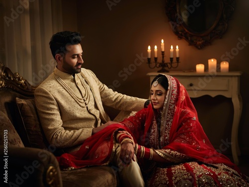 Indian wedding couple in traditional ethnic attire sitting together in a candlelit room