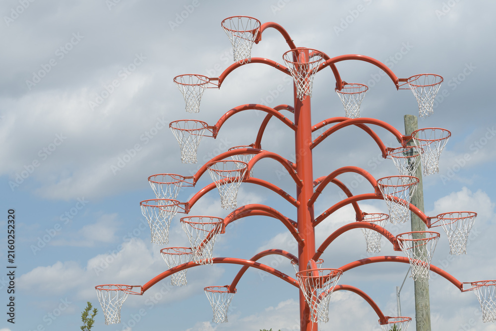 Fototapeta premium view of Alexandre Arrechea's Orange Functional, 2022, composed of steel and basketball nets, #1, in the plaza of Old Firehall 30, at Biidaasige Park, Port Lands, Toronto