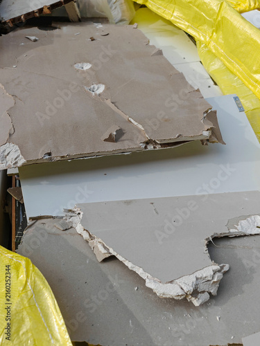Broken sheetrock and construction debris in yellow disposal bag during home remodeling project