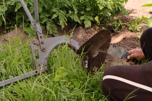 фотографія Farmer cleans the share of a hand plow with a spatula against the background of