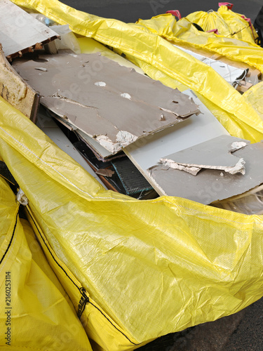 Broken sheetrock and construction debris in yellow disposal bag during home remodeling project