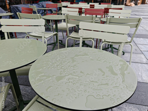 Outdoor cafe table with spilled water droplets on white surface in sunlight after heavy rain