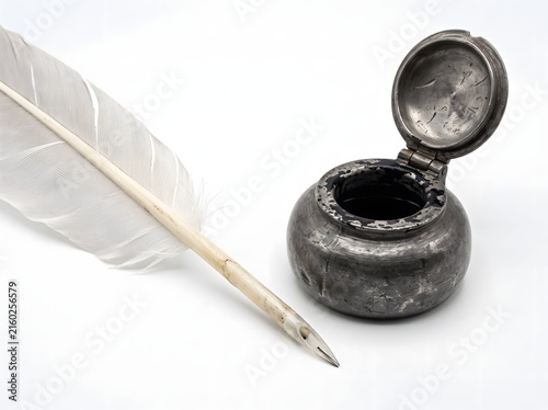 Quill pen and antique inkwell rest on a white surface