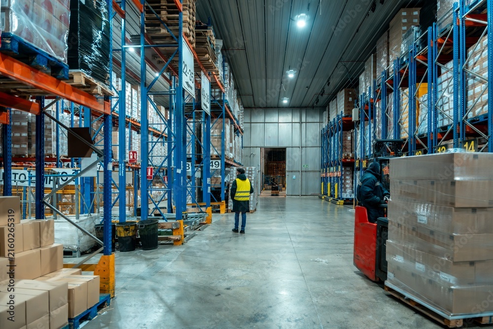Naklejka premium Warehouse worker operating forklift for loading pallets in distribution center with forklift, warehouse