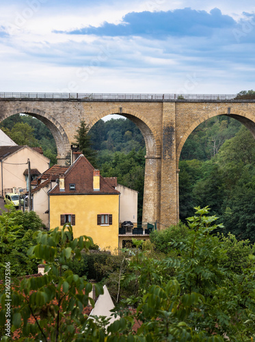 Scenic landscape view with a tall stone arch viaduct bridge over a wooded river valley