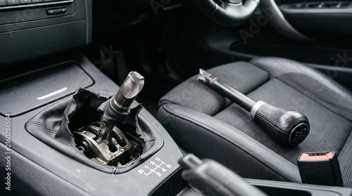 Broken car gear shifter lever damaged manual transmission stick lying on passenger seat inside vehicle cabin. Auto repair concept detailing mechanical failure and transmission problems.