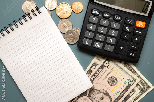 Cuadro en lienzo Calculator with US dollar banknotes, coins and blank lined notebook arranged as a budgeting and financial planning concept with useful copy space