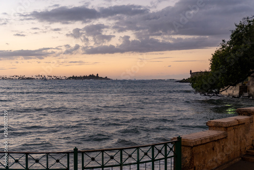 San Juan, Puerto Rico waterfront at end of Paseo de la Princesa near Fuente Raíces. Sunset views of bartizan sentry box on the El Morro Paseo walkway and Fortín San Juan de la Cruz or El Cañuelo.
