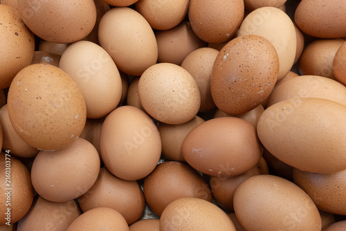 Abundant pile of fresh brown organic chicken eggs with natural light creating a warm and inviting natural food background