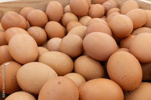 Abundant pile of fresh brown chicken eggs in rustic wooden crate natural light and wholesome organic food concept