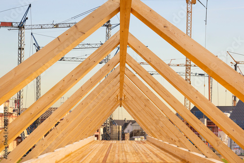Auf dem Dach von einem Wohnhaus wird von einem Zimmermann der Dachstuhl mit Holzbalken gebaut - FOTOMONTAGE
