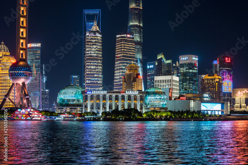 The brightly illuminated Pudong skyline, featuring the iconic Oriental Pearl Tower, casts colorful reflections across the Huangpu River at night. China, Shanghai - 14 November 2025