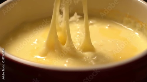 Delicious creamy Swiss cheese fondue bubbling and melting in a warm pot, providing a rich, savory dipping sauce for a traditional meal or appetizer.