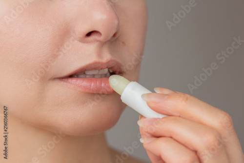 Obraz na płótnie Close up of woman applying hygienic moisturizing lip balm pomade stick