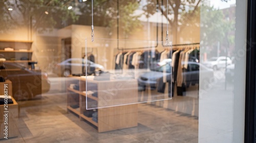 Modern boutique clothing store window display with hanging sign and apparel racks