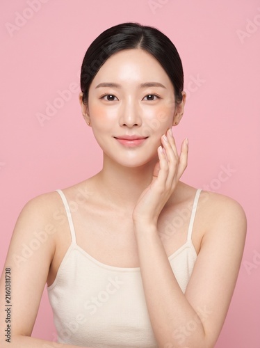 Beautiful young woman touching her smooth face with clean skin and healthy glow