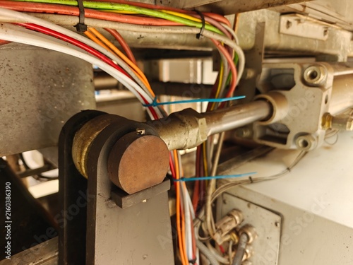 A metal pin on a structural part with a hydraulic cylinder and wiring in a machine.