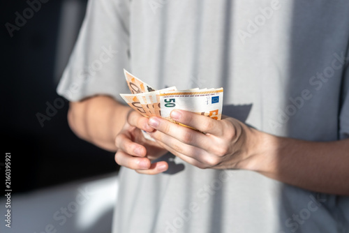 фотографія Hands holding and counting fifty euro banknotes