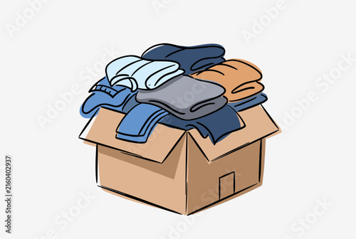 Cardboard box overflowing with neatly folded clothing items as donations or packing for a house moving day.