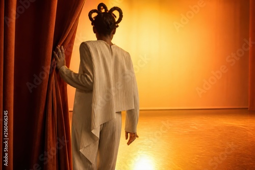 Backstage performer opening curtain on warm theatre stage