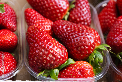 Strawberries in a plastic container, at a street market, in a supermarket.