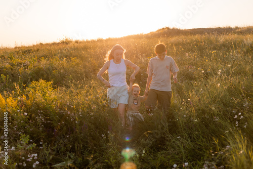 Quadro su tela happy mother with two sons in the summer at sunset