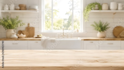 Rustic wooden table surface with blurry kitchen counter background featuring white cabinets and fresh green plants.