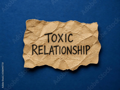Toxic relationship text on crumpled paper. Emotional abuse concept on torn craft note.