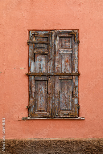 Vintage wooden window on a weathered plaster wall of an historic house