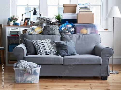 Household belongings stacked on sofa and shelves in rented apartment during daylight