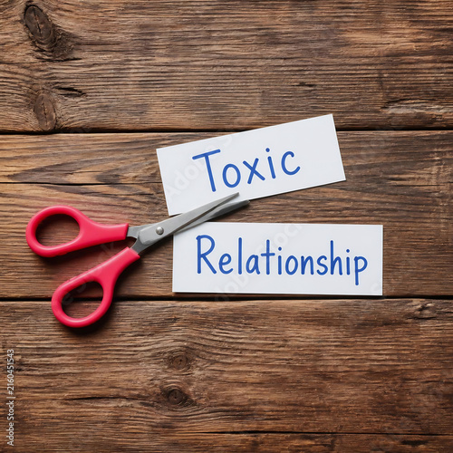 Pink scissors cutting paper with toxic relationship text. Ending bad connection concept.