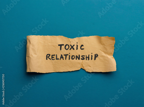 Toxic relationship text on torn paper. Conceptual sign about unhealthy emotional connection.