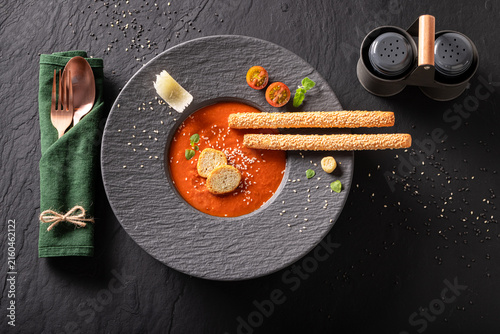 Professional and healthy tomato soup with high-end presentation on plate.