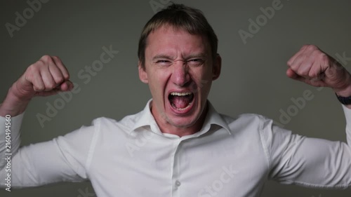 Excited businessman celebrating success with raised fists and joyful facial expression. Studio portrait isolated on a white background, perfect for business success, achievement and victory concepts.