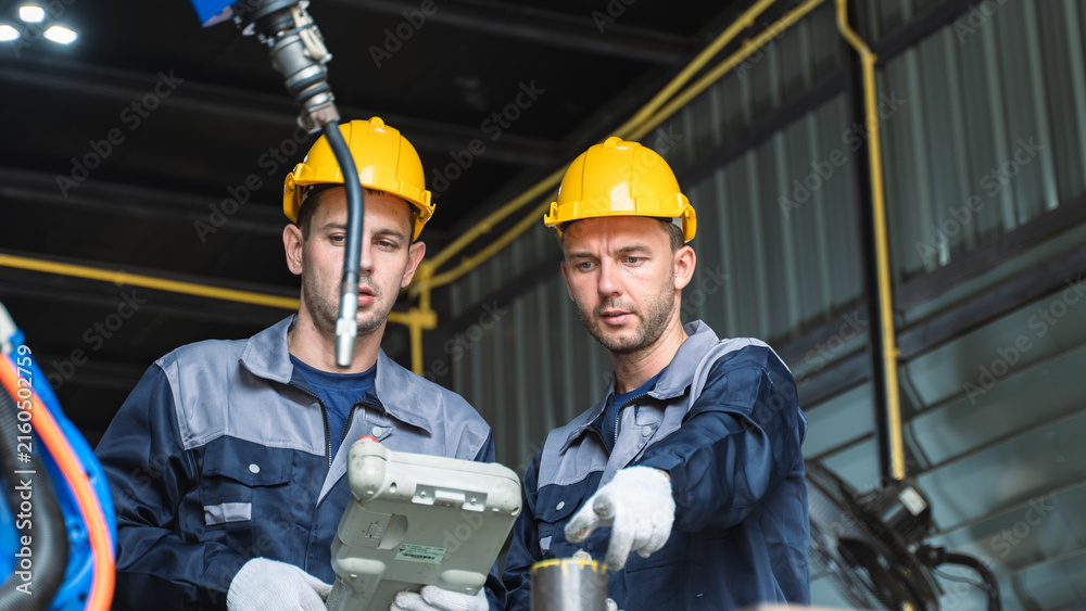 Fototapeta premium Maintenance engineer checking a robot controller on Robotic Production Equipment Inside a Modern Factory While Reviewing Automation Controls