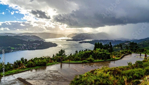 Scenic coastal landscape under dramatic storm clouds and sunlight.