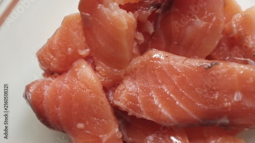 Fresh raw salmon fillets, sliced and lightly seasoned with salt, rest inside a clear glass dish in a close-up macro shot. For culinary commercials, seafood recipe tutorials, healthy eating promotions.
