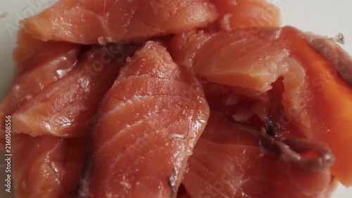 Fresh raw salmon fillets, sliced and lightly seasoned with salt, rest inside a clear glass dish in a close-up macro shot. For culinary commercials, seafood recipe tutorials, healthy eating promotions.