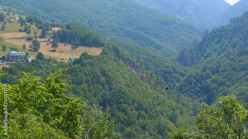 Scenic mountain valley landscape with forested slopes. Beautiful panoramic view of a green mountain valley with lush forests, rolling hills, and a small village nestled in the landscape