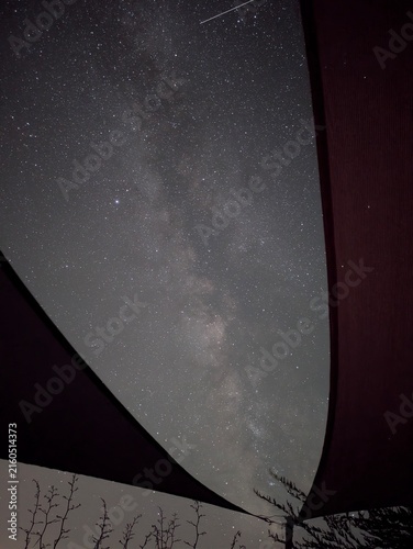 Photography Voie lactée clairement visible dans un ciel nocturne très étoilé, photographiée entre des toiles d'ombrage formant un cadre graphique autour du ciel