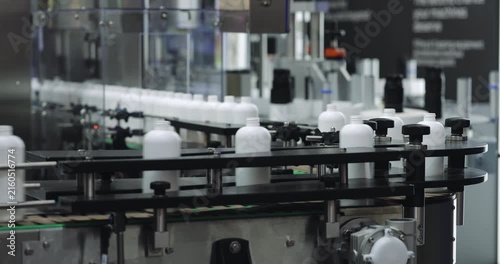 Plastic containers for household chemicals circulate on factory conveyor during packaging. Advanced production equipment supports high-speed manufacturing