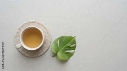 Coffee Cup on Coaster with Green Leaf on Neutral Background