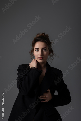 Fotografie Woman poses in a black blazer with a neutral background in a studio setting